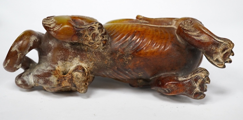 A Chinese archaistic pale celadon russet and burnt jade figure of a winged mythical beast, wood stand, mythical beast 12cm wide. Condition - carving good, stand good
